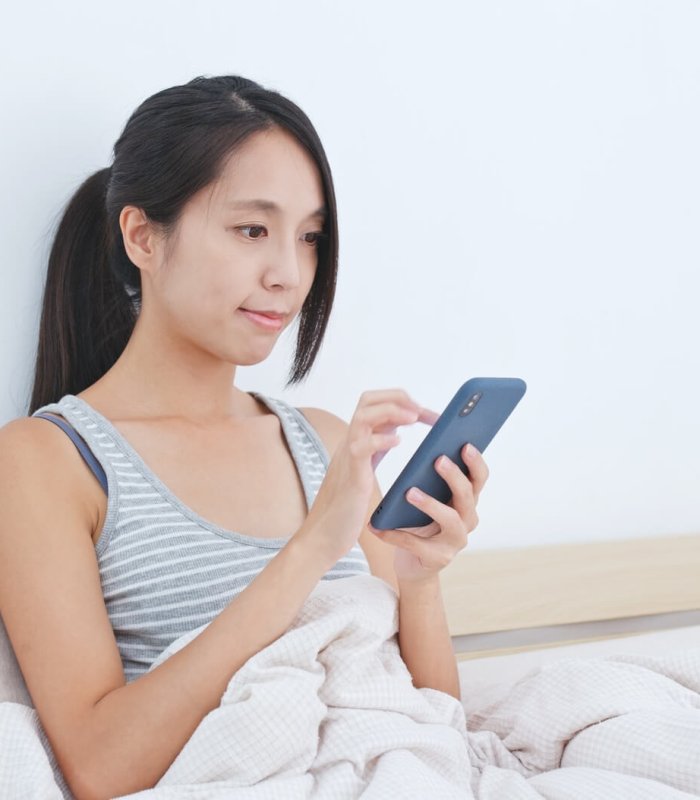 Woman using mobile phone app to control the lighting at home, smart home concept