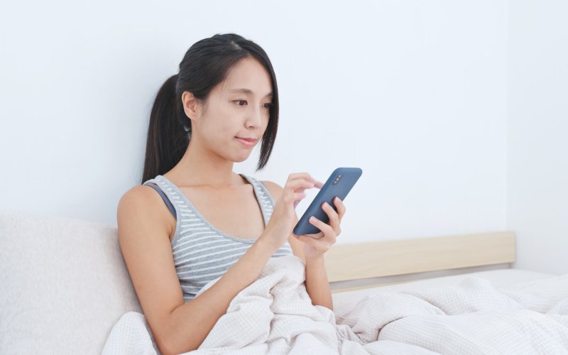 Woman using mobile phone app to control the lighting at home, smart home concept