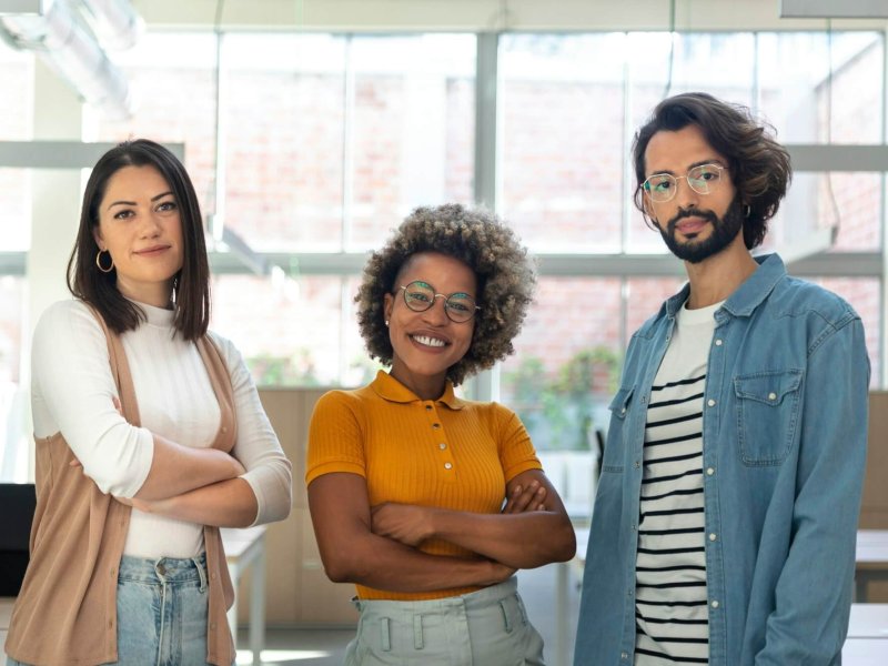 Multiracial coworkers looking at camera standing in bright spacious co working office space.