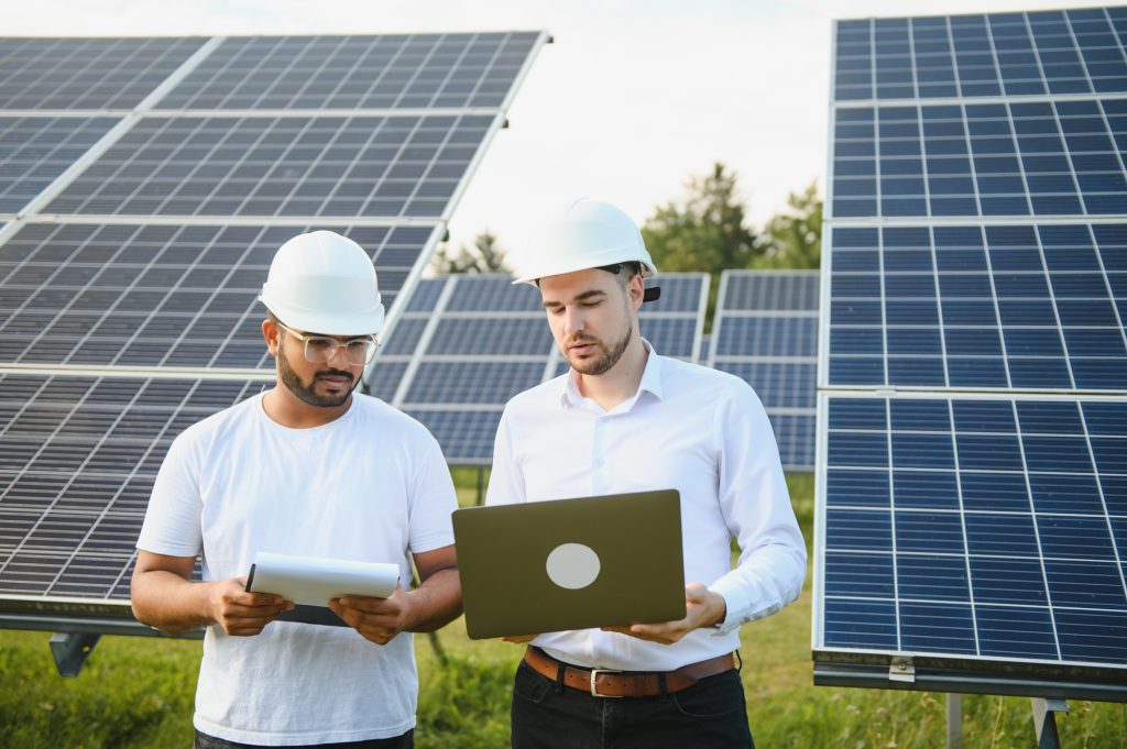Two engineers or businessmen on the background of solar panels. Renewable energy. Green energy