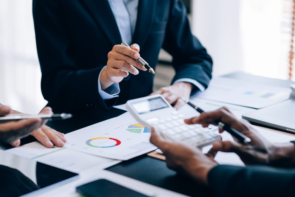 Close up view of businesspeople or accountant team working on financial investment on calculator in