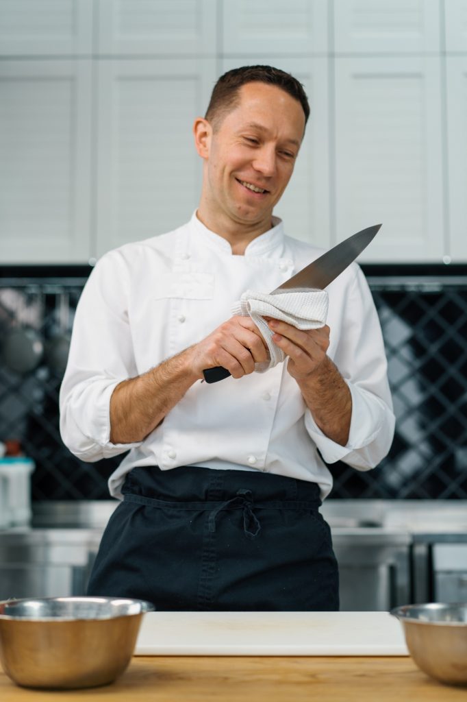 professional kitchen chef wipes clean knife after cooking breakfast healthy food concept