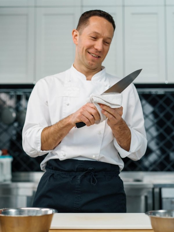 professional kitchen chef wipes clean knife after cooking breakfast healthy food concept