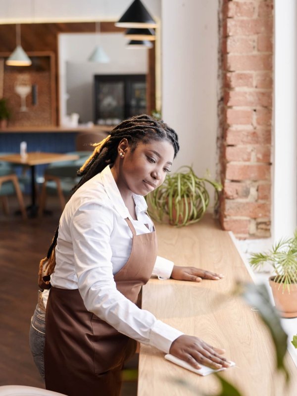 Young Black Waitress Cleaning Table