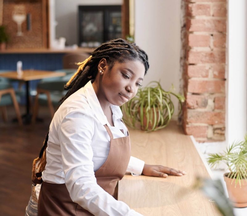 Young Black Waitress Cleaning Table