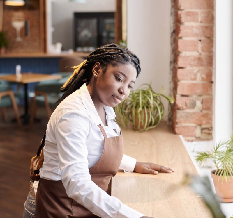 Young Black Waitress Cleaning Table