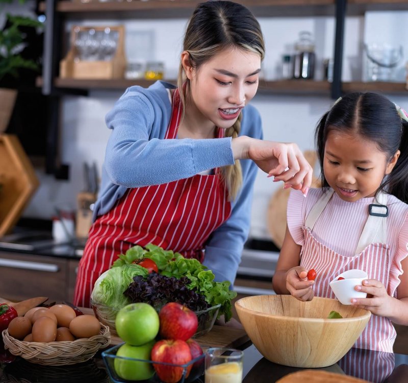 Young mother teach daughter in the kitchen learn online cooking clean food from the laptop computer