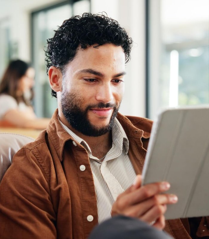 Man, relax and smile on sofa with tablet, social media and research for new home improvement. Perso