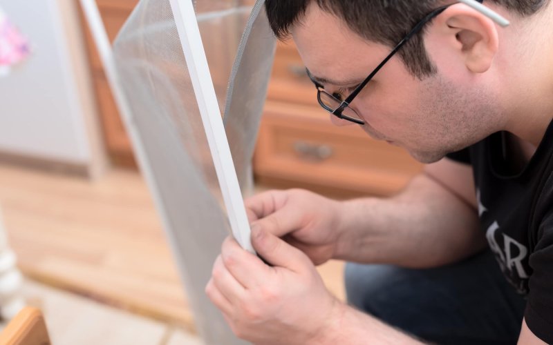 Man repairing mosquito net at home. Home improvement concept.