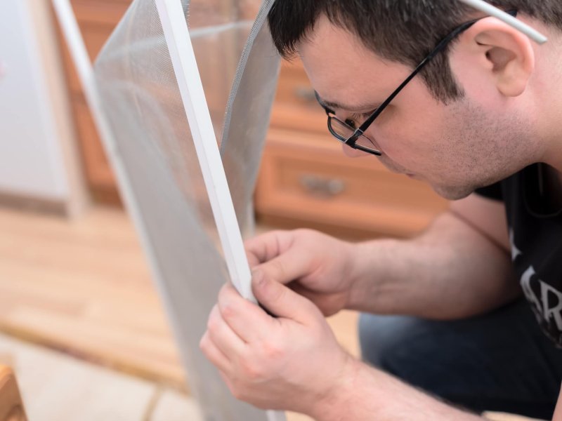 Man repairing mosquito net at home. Home improvement concept.