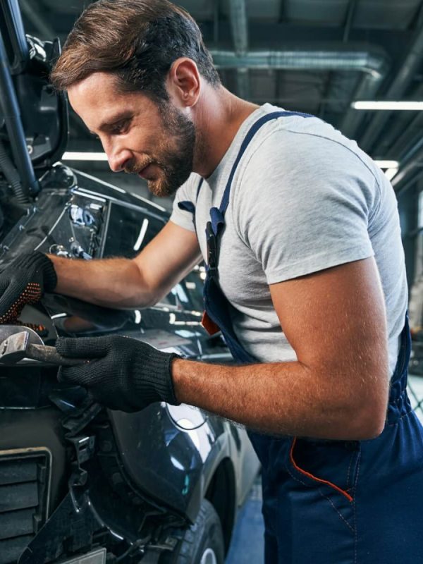 pleased-automotive-repairman-flattening-component-part-of-car