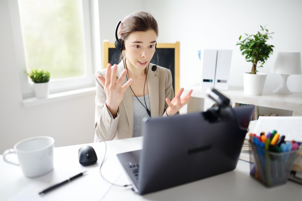 Young woman is learning language with laptop computer, camcorder and headphone online at home.