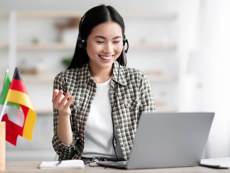 Happy asian lady using laptop and headset, learning foreign language