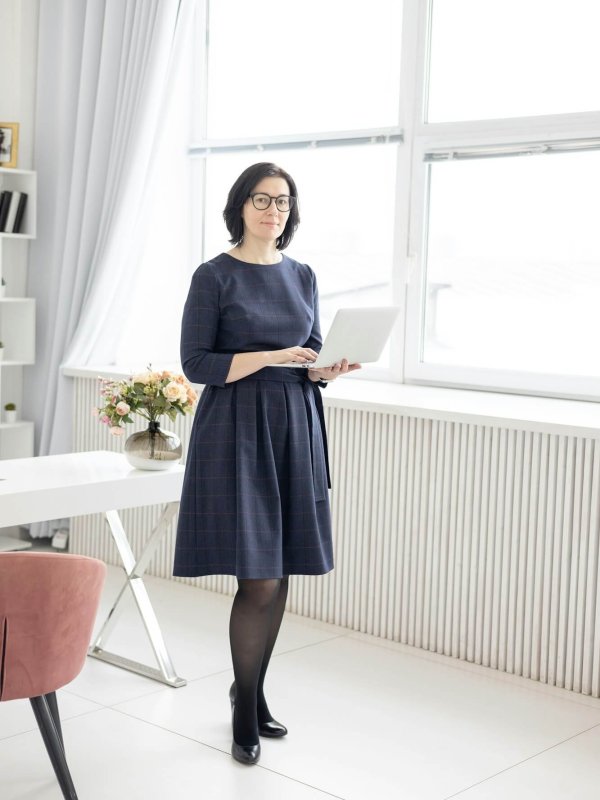 a young woman in glasses and in a blue shirt works at home at a laptop as a coach