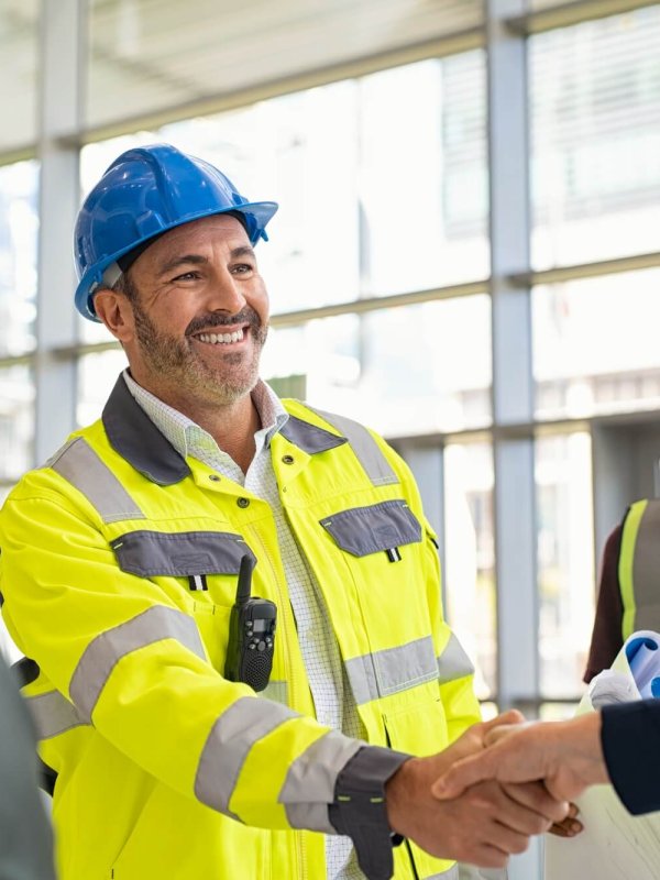 Mature architect and contractor shaking hands at construction site