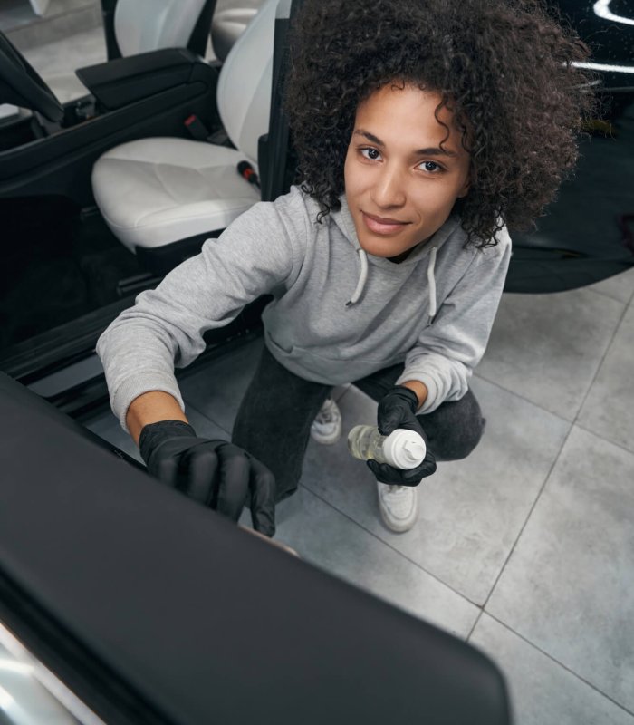 Pleased auto detailer brushing car door panel