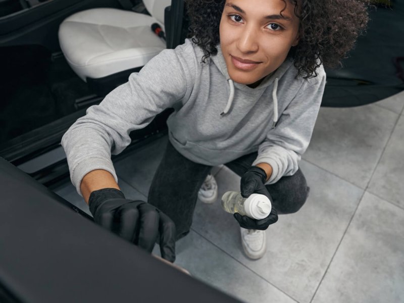 Pleased auto detailer brushing car door panel