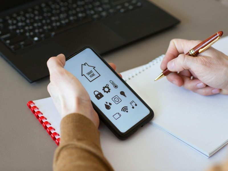 man-controls-smart-home-devices-using-app-for-mobile-phone-on-background-of-businessman-s-work-table