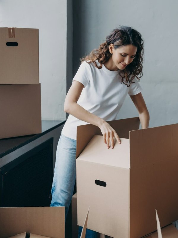 Female volunteer packing donation box for refugees, looks into parcel package. Delivery, charity