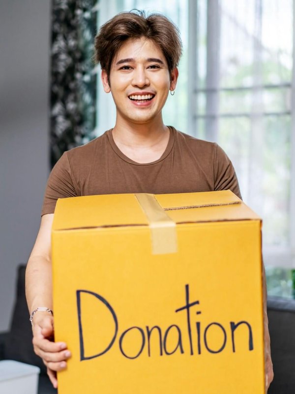 Happy volunteer asian man holding a Donate Box for Giving, Smiling male working at charity center.