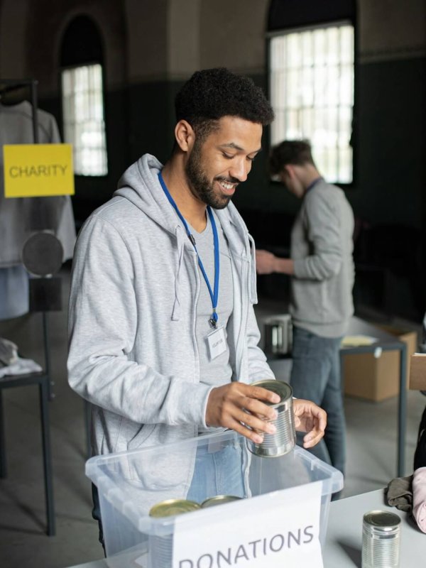 Volunteers working in community charity donation center., sorting out clothes and canned food.