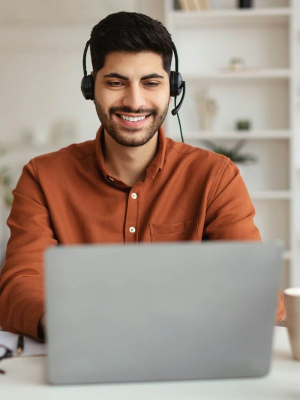 Arab man using laptop wearing headset sitting at desk
