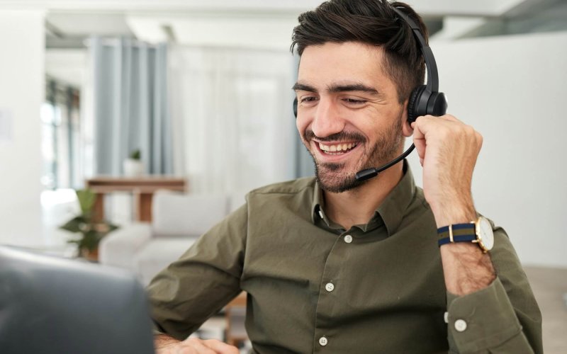 Man, remote work and virtual assistant with headphones at laptop for video call, voip communication